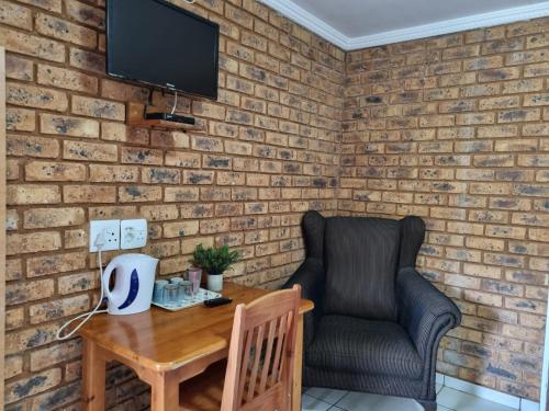 a brick wall with a chair and a wooden table at Airport Inn Bed and Breakfast in Kempton Park