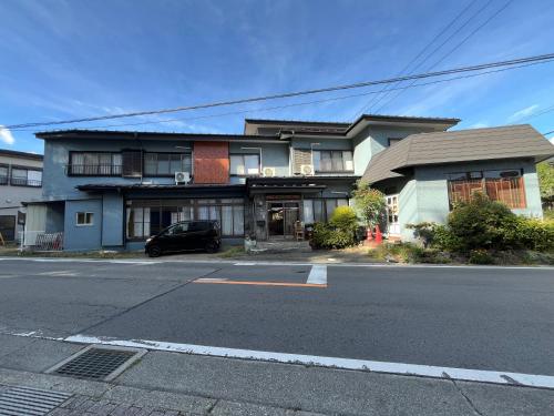 a house with a car parked in front of a street at ふる里 Mt Fuji Inn Furusato in Fujikawaguchiko