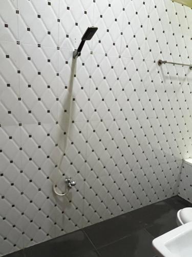 a bathroom with a toilet and a white tiled wall at Kalinga Art Home Guest House in Siem Reap