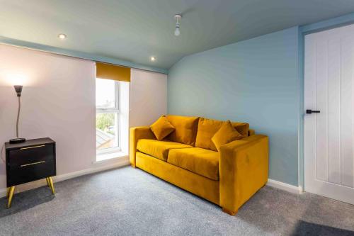 a yellow couch in a room with a window at Elderberry Hall The Ultimate Family Reunion HQ in Fishburn