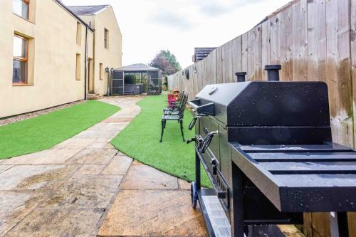 a barbecue grill in a garden with a fence at Elderberry Hall The Ultimate Family Reunion HQ in Fishburn