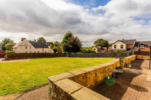 a stone retaining wall with a bench in a yard at Elderberry Hall The Ultimate Family Reunion HQ in Fishburn
