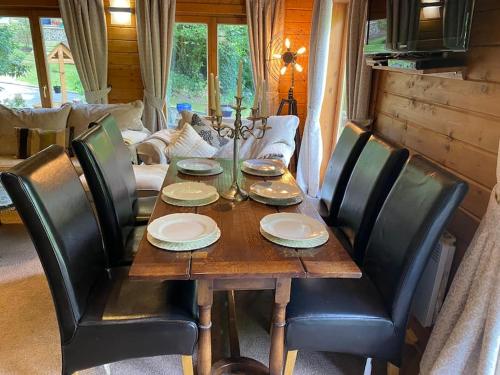 einen Holztisch mit schwarzen Stühlen und ein Esszimmer in der Unterkunft 3 Bedroom Lodge Hotub pool in Horsley Surrey UK in East Horsley