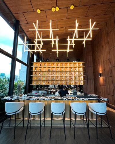 a bar in a restaurant with white chairs and lights at B Hotel Kuala Lumpur in Kuala Lumpur