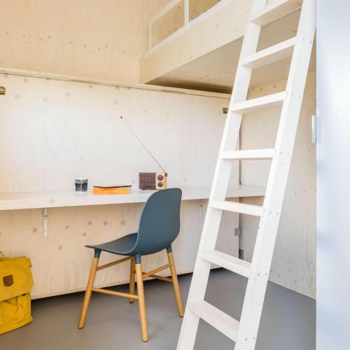 a desk and a chair in a room with a ladder at Florizand - Ecohuisjes Terschelling in Midsland
