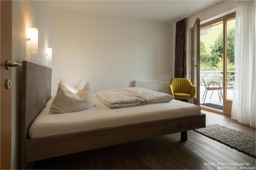 a bed in a room with a window and a chair at Appartments Gerlos Am Bach - Riverside in Gerlos