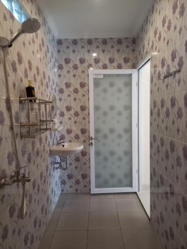 a bathroom with a door leading to a sink at Prayoga homestay in Nusa Dua
