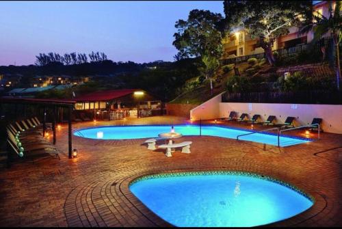 a large swimming pool with a table and chairs next to a building at Shakas rock chalet 20 in Ballito