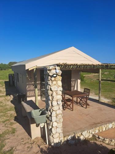 a gazebo with a picnic table and a stone wall at Thali Thali Game Lodge in Langebaan