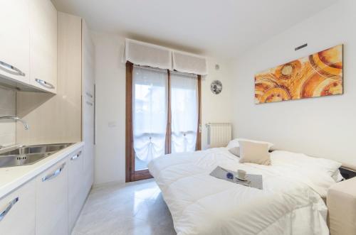 a white bedroom with a bed and a sink at Residence Daytona Appartamento due camere in Caorle