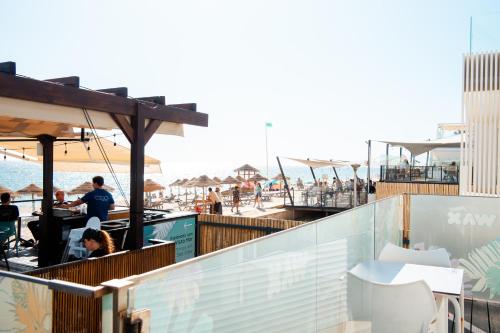 people sitting at tables on a patio near the beach at Wax Suite Life is a beach in Faro