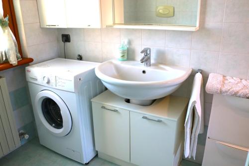 a bathroom with a sink and a washing machine at Casa Fiorella - Appartamento - Parcheggio gratuito in Beccacivetta