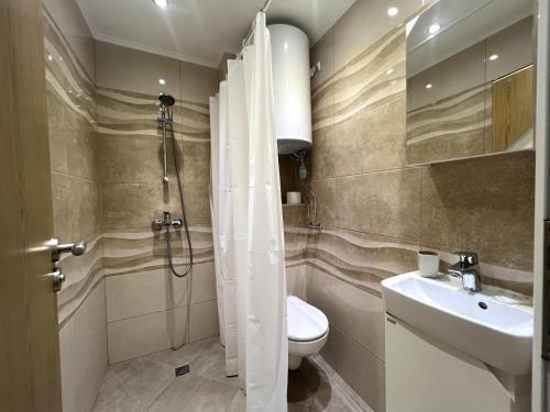 Un baño con ducha, inodoro y lavabo. en Luxury apartmemts, en Burgas