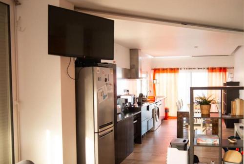 a kitchen with a stainless steel refrigerator with a flat screen tv at Wax Suite Life is a beach in Faro