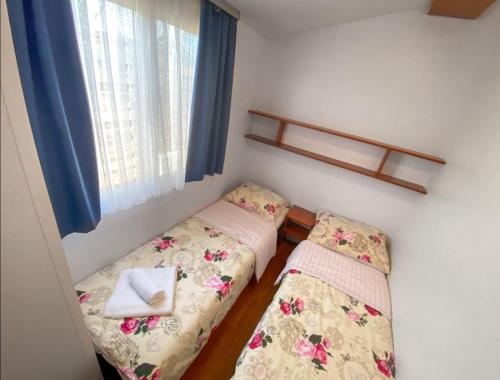 a small room with two beds and a window at Mobilheim Camping 6 Personen Pool am Meer in Turanj