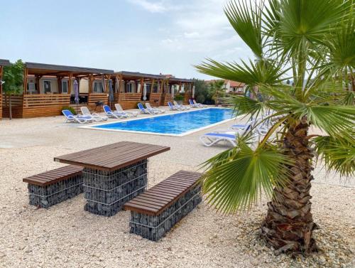 a pool with a table and chairs and a palm tree at Mobilheim Camping 6 Personen Pool am Meer in Turanj