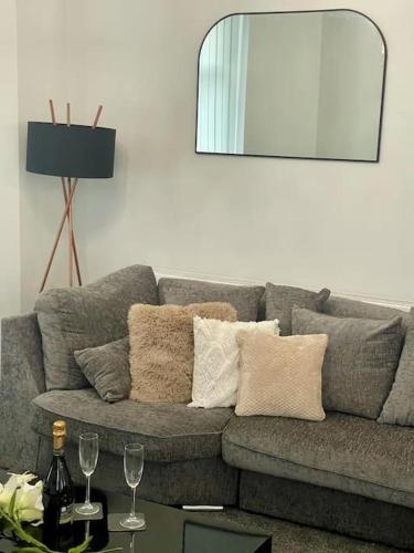 a living room with a gray couch with two wine glasses at Haven Hideout 4 Bed With Sauna, Cinema & Gym in Royton