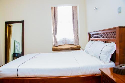 a bedroom with a bed with a mirror and a window at The Blixen Resort & Spa in Nairobi