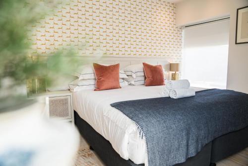 a bedroom with a large bed with orange pillows at Linhay Cottages 1 in Bathford