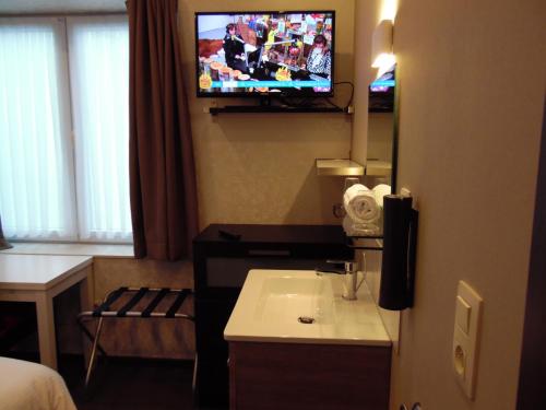 a hotel room with a sink and a tv on the wall at Vakantielogies Cathedral in Ghent