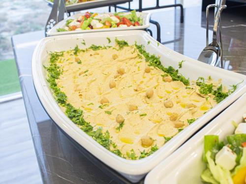 a casserole dish of food on a table with vegetables at Veliton Hotel in Al Khobar