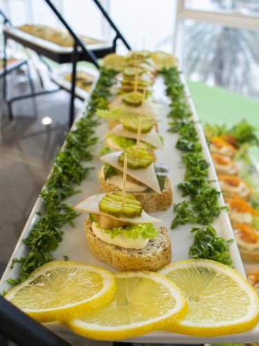a row of sandwiches on a tray with lemon slices at Veliton Hotel in Al Khobar