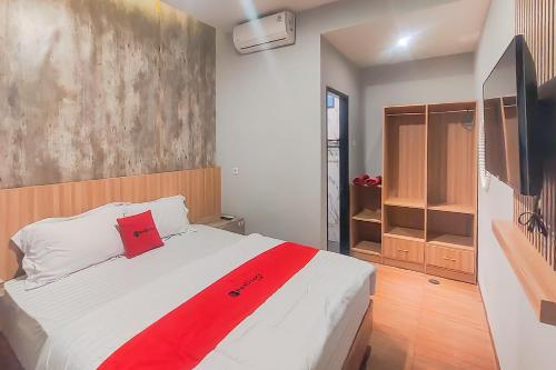 a bedroom with a large white bed with a red blanket at RedDoorz Syariah near Ponpes Hidayatullah Samarinda in Samarinda