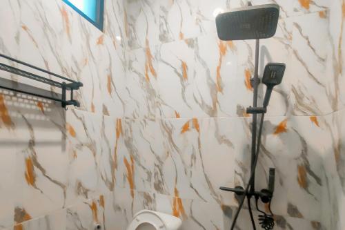 a bathroom with a shower with a hair dryer on the wall at RedDoorz Syariah near Ponpes Hidayatullah Samarinda in Samarinda