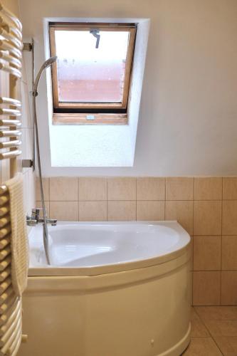 a bath tub in a bathroom with a window at Trón Apartman 2 in Siklós