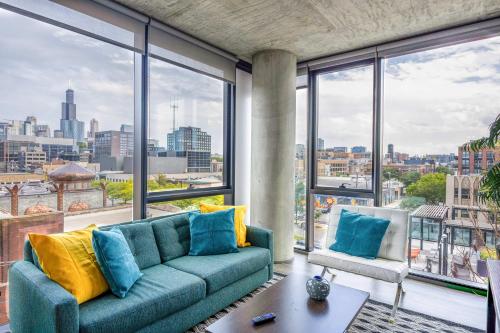 a living room with a blue couch and large windows at New Sleek 2BR - Perfect Blend of Comfort & Style in Chicago in Chicago
