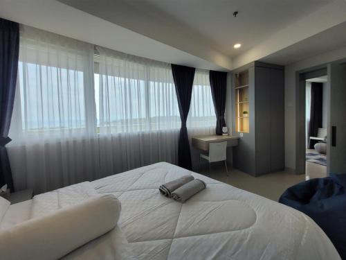 ein Schlafzimmer mit einem großen weißen Bett und einem Schreibtisch in der Unterkunft Apartment Nuvasa Bay Nongsa, Kalani 1BR 12th, Sea & Golf View in Telukmataikan