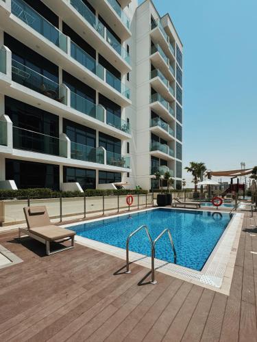 a swimming pool in front of a large building at VESTA - Dubai Residence in Dubai