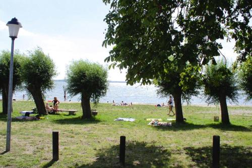 a group of people sitting in a park near the water at Cottages at the Kummerower See Verchen in Verchen