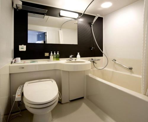 a bathroom with a toilet and a sink and a tub at Smile Hotel Tokushima in Tokushima
