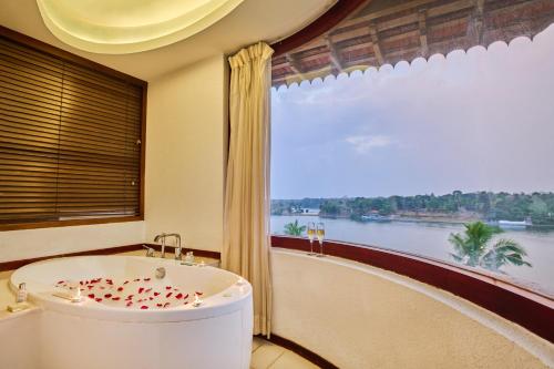 Una bañera en una habitación con una ventana grande. en The Leela Ashtamudi, A Raviz Hotel, en Kollam