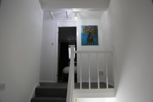 a staircase in a house with a painting on the wall at 3BR Luxury Stay Near Billing Aquadrome - Elegant 3-Bedrooms One-and-Half Bathrooms Home - Sleeps 8 - Free Parking and Complimentary Access to Billing Aquadrome Holiday Village in Northampton