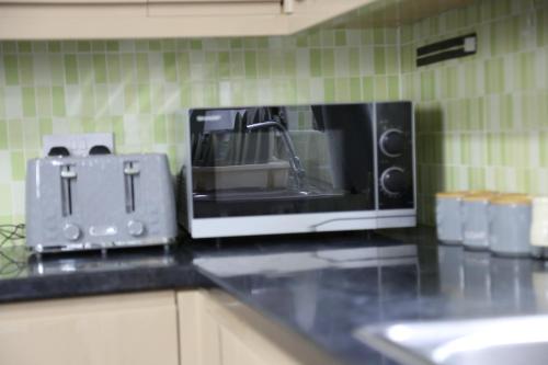a microwave sitting on top of a kitchen counter at 3BR Luxury Stay Near Billing Aquadrome - Elegant 3-Bedrooms One-and-Half Bathrooms Home - Sleeps 8 - Free Parking and Complimentary Access to Billing Aquadrome Holiday Village in Northampton