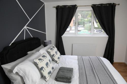 a bedroom with a bed with black curtains and a window at 3BR Luxury Stay Near Billing Aquadrome - Elegant 3-Bedrooms One-and-Half Bathrooms Home - Sleeps 8 - Free Parking and Complimentary Access to Billing Aquadrome Holiday Village in Northampton