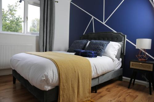 a bedroom with a bed with a blue wall at 3BR Luxury Stay Near Billing Aquadrome - Elegant 3-Bedrooms One-and-Half Bathrooms Home - Sleeps 8 - Free Parking and Complimentary Access to Billing Aquadrome Holiday Village in Northampton