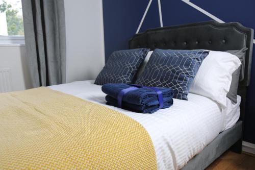 a bed with two pillows and a bag on it at 3BR Luxury Stay Near Billing Aquadrome - Elegant 3-Bedrooms One-and-Half Bathrooms Home - Sleeps 8 - Free Parking and Complimentary Access to Billing Aquadrome Holiday Village in Northampton