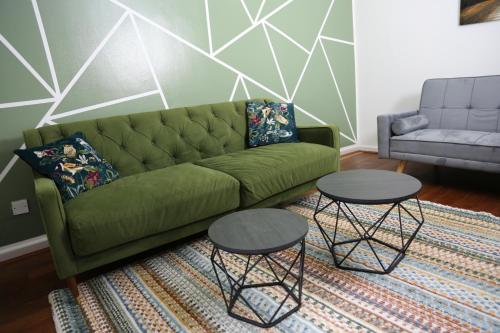 a living room with a green couch and two tables at 3BR Luxury Stay Near Billing Aquadrome - Elegant 3-Bedrooms One-and-Half Bathrooms Home - Sleeps 8 - Free Parking and Complimentary Access to Billing Aquadrome Holiday Village in Northampton