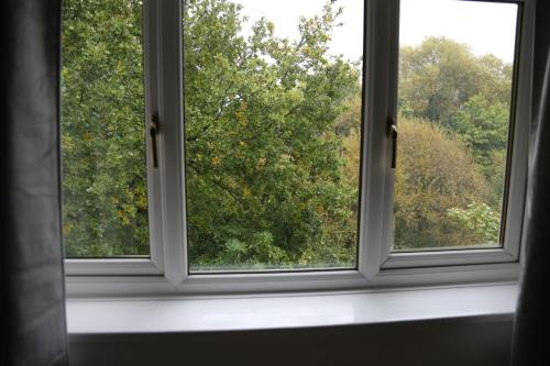 an open window with a view of trees at 3BR Luxury Stay Near Billing Aquadrome - Elegant 3-Bedrooms One-and-Half Bathrooms Home - Sleeps 8 - Free Parking and Complimentary Access to Billing Aquadrome Holiday Village in Northampton