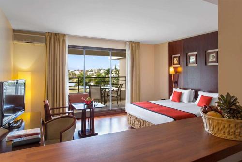 una camera d'albergo con un letto e un balcone di Ramada Hotel & Suites by Wyndham Noumea a Noumea
