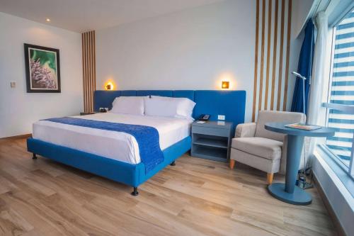 a bedroom with a blue bed and a chair at Wyndham Guayaquil, Puerto Santa Ana in Guayaquil