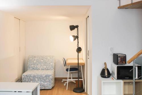 Cette chambre comprend un bureau, une chaise et une lampe. dans l'établissement Charming apartment near Buttes-Chaumont, à Paris