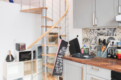 une cuisine avec des placards blancs et un escalier en colimaçon dans l'établissement Charming apartment near Buttes-Chaumont, à Paris