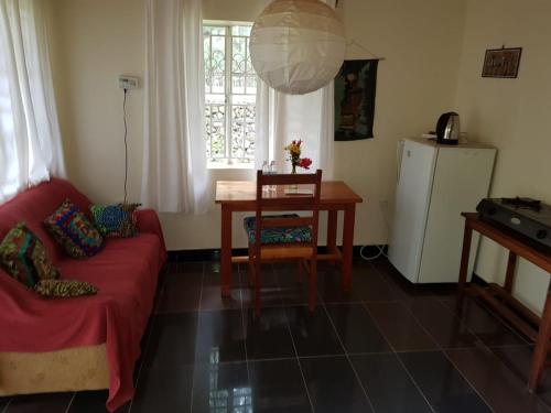 a living room with a red couch and a table at Mutolere Coffee Pot Guest Houses in Kisoro