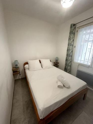 une chambre avec un lit avec des draps blancs et une fenêtre dans l'établissement La villa bleue Arles jardin, à Arles