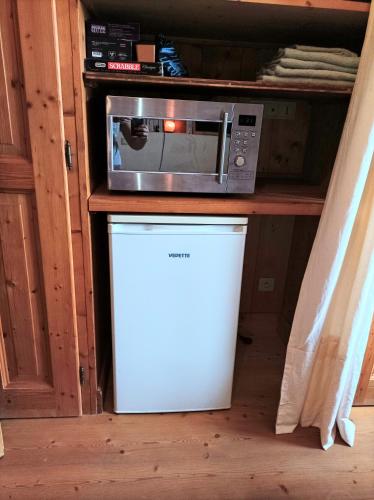 Un four micro-ondes est installé au-dessus d'un réfrigérateur blanc. dans l'établissement Jolie chambre châlet Chez Marine, à Gilly-sur-Isère