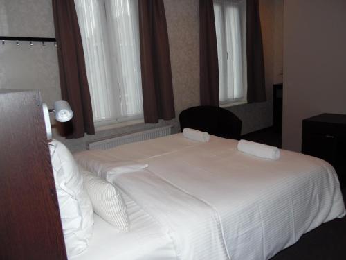 a bedroom with a white bed with a chair and windows at Vakantielogies Cathedral in Ghent